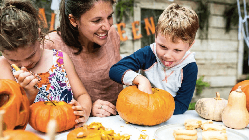 Woman and two kids carving pumpkin lanterns