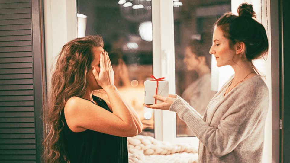 Woman gives white gift box to other woman