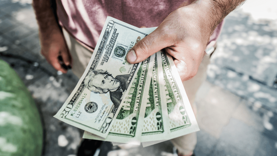 Man holding 20 dollar bills in hand