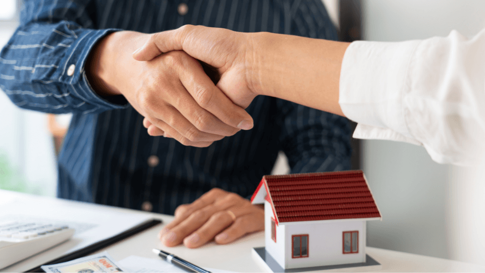 Man shaking hand with home on desk