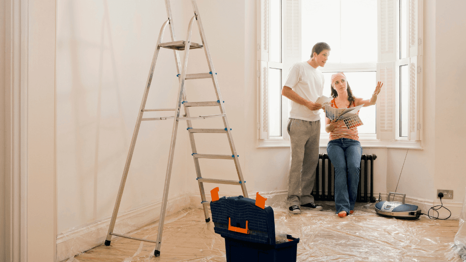 Man and women in front of the window in a clear room with ladder and toolbox