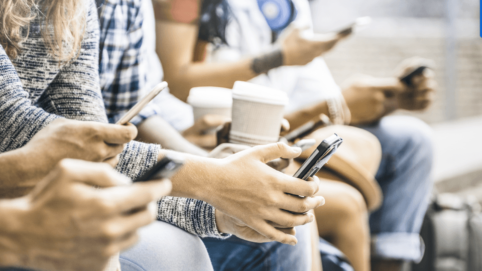People sitting on a bench with coffee and smartphones