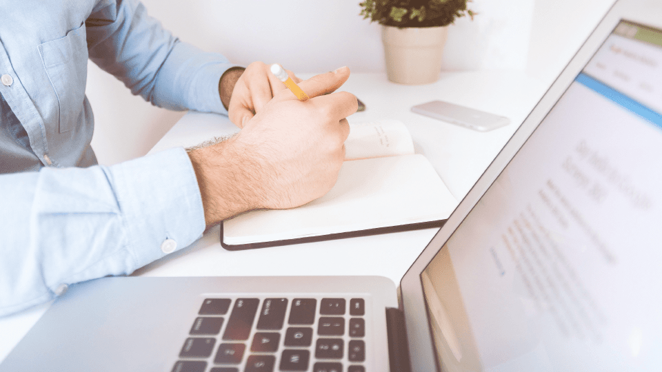 Man working at the desk with notebook, laptop and flower pot