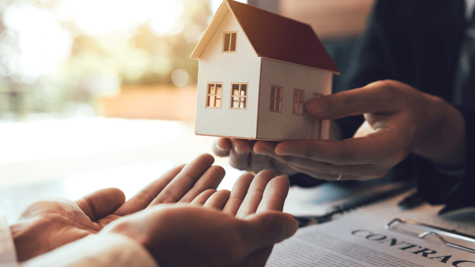 Two people holding home model over lease contract