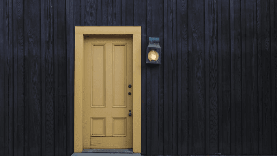 Yellow door in black wall with lantern