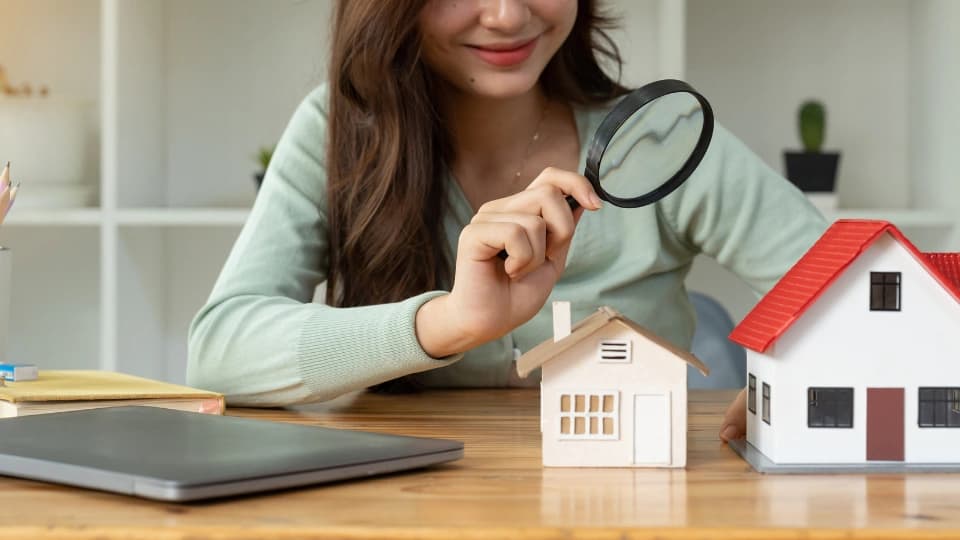 Woman looking at house through a microscope