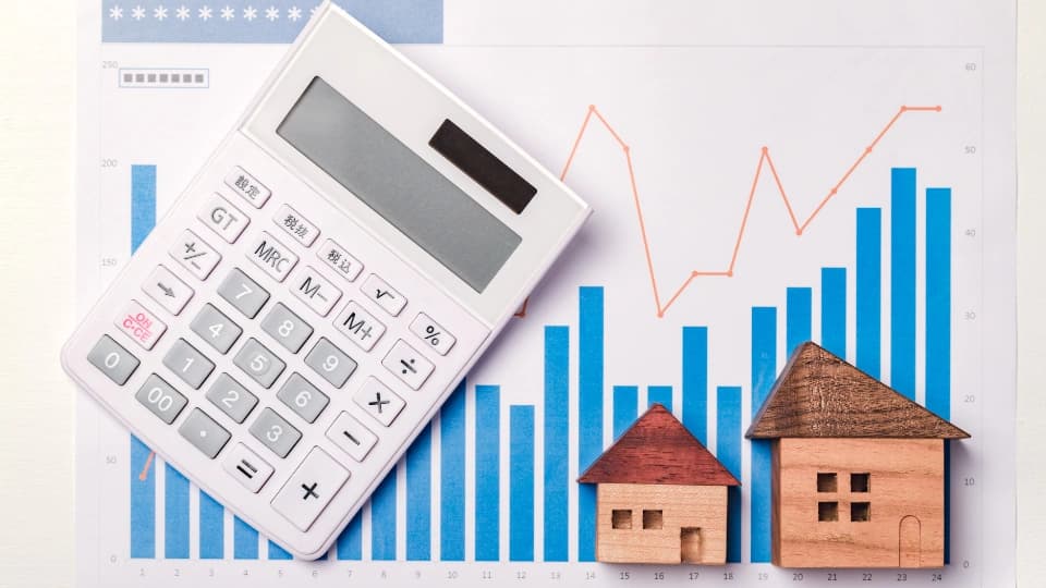 Calculator on a graph with two wooden homes