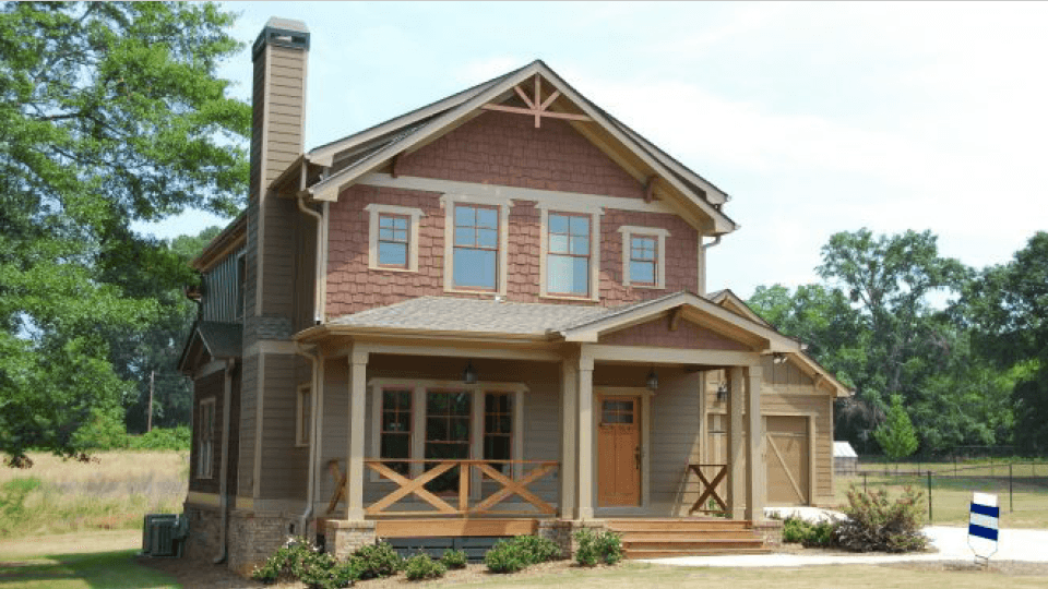 House with porch, lawn and trees around
