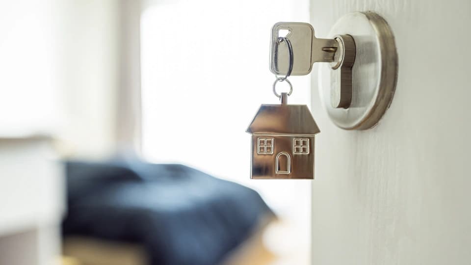 Open the door and door handle with a key and a keychain shaped house. Property investment and property management concept.