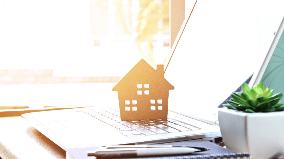 Computer with a miniature house on top of it all placed on a desk