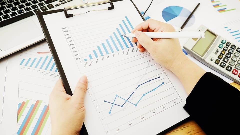 person pointing to graphs on paper