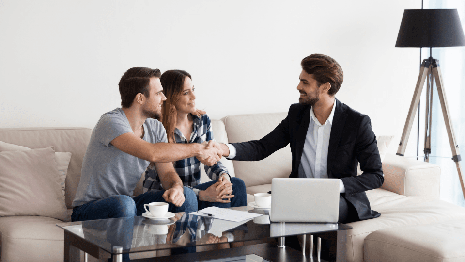 Couple shaking hands with man in suit