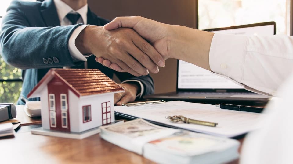 two people shaking hands over a desk