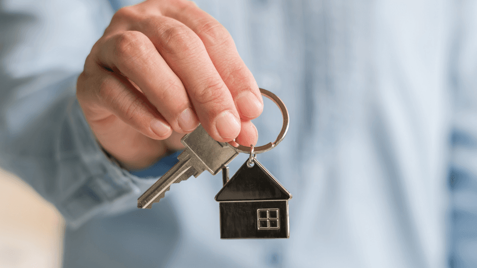 Person holding a set of keys with a house keychain