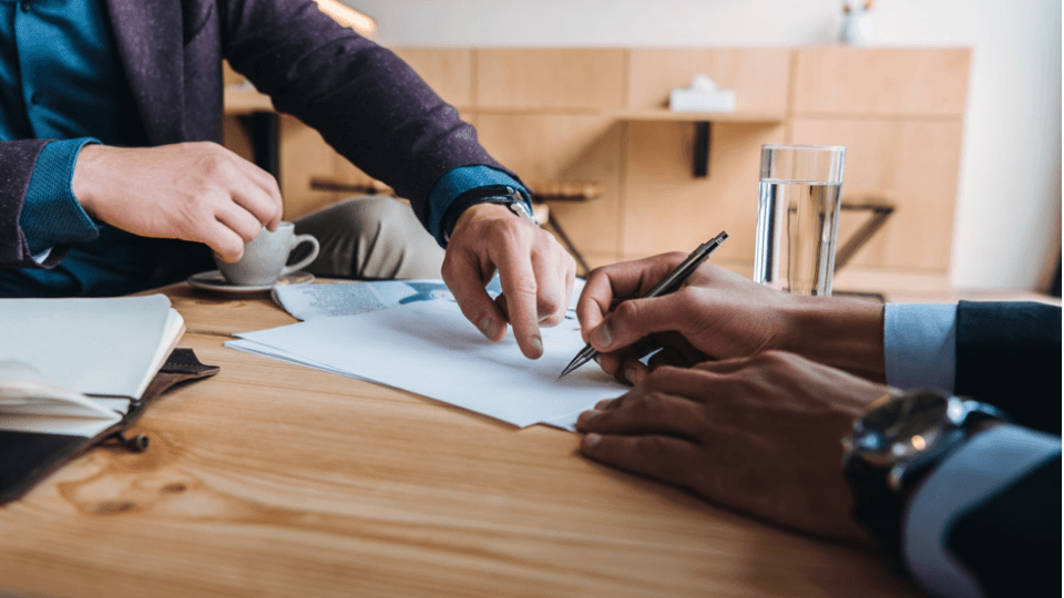 Two mens with papers and glass of water and cup of coffee on the table