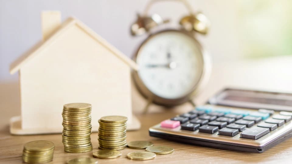 Coins, house, calculator and a clock on a table