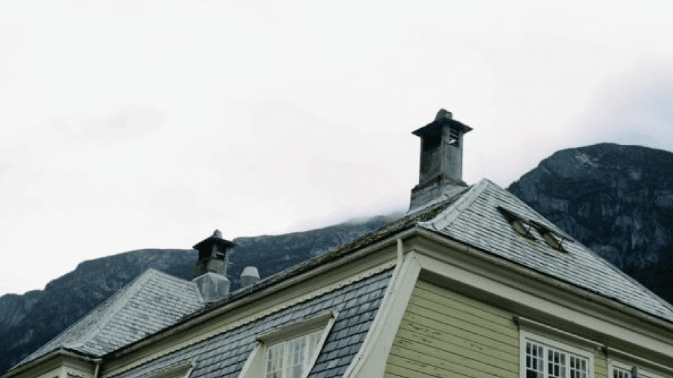House roof with with mountains behind it