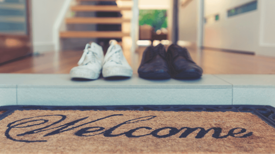 Welcome mat with two pairs of shoes in an entry way