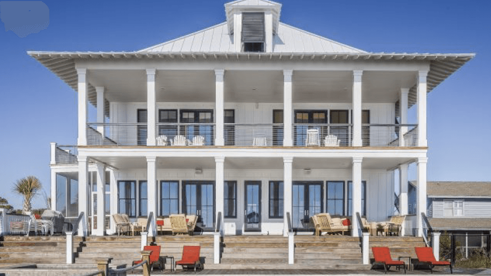 White house with large porch and balcony with a lot if chairs